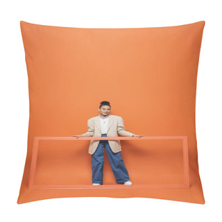 Personality  Smiling African American Model In Beige Blazer And Blue Pants Holding Frame On Orange Backdrop Pillow Covers