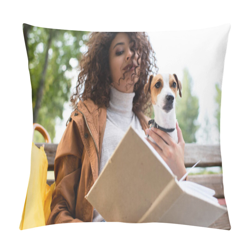 Personality  low angle view of curly woman holding jack russell terrier dog while reading book in park pillow covers