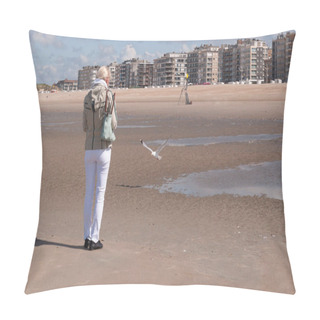 Personality  A Woman Stands With Her Back And Feeds A Seagull On A Sandy Beach In Ostend,residential Buildings Are Visible In The Distance Pillow Covers