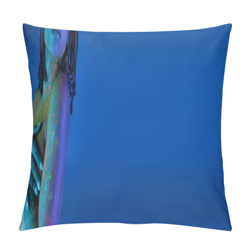 Personality  partial view of youthful african american woman with dreadlocks posing in colorful neon body paint on blue background with cyan lighting effect, banner pillow covers