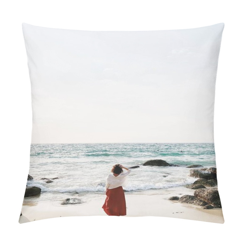 Personality  A beautiful young woman in red skirt and white shirt standing on the beach watching at blue sea with waves, rocks and cream sky. Open space for text. Summer and travel concept. pillow covers