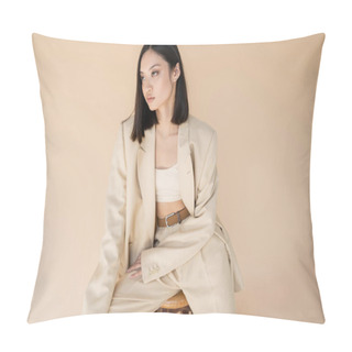 Personality  Trendy Asian Woman In Ivory Suit Sitting On Stool And Looking Away Isolated On Beige Pillow Covers