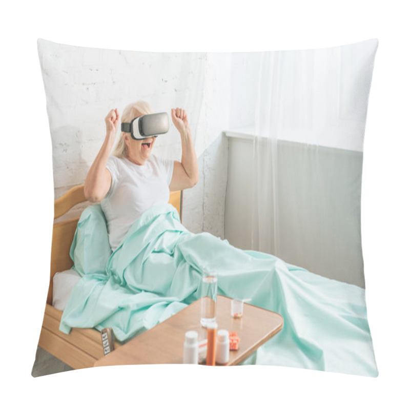 Personality  excited senior woman in virtual reality headset lying in hospital bed  pillow covers