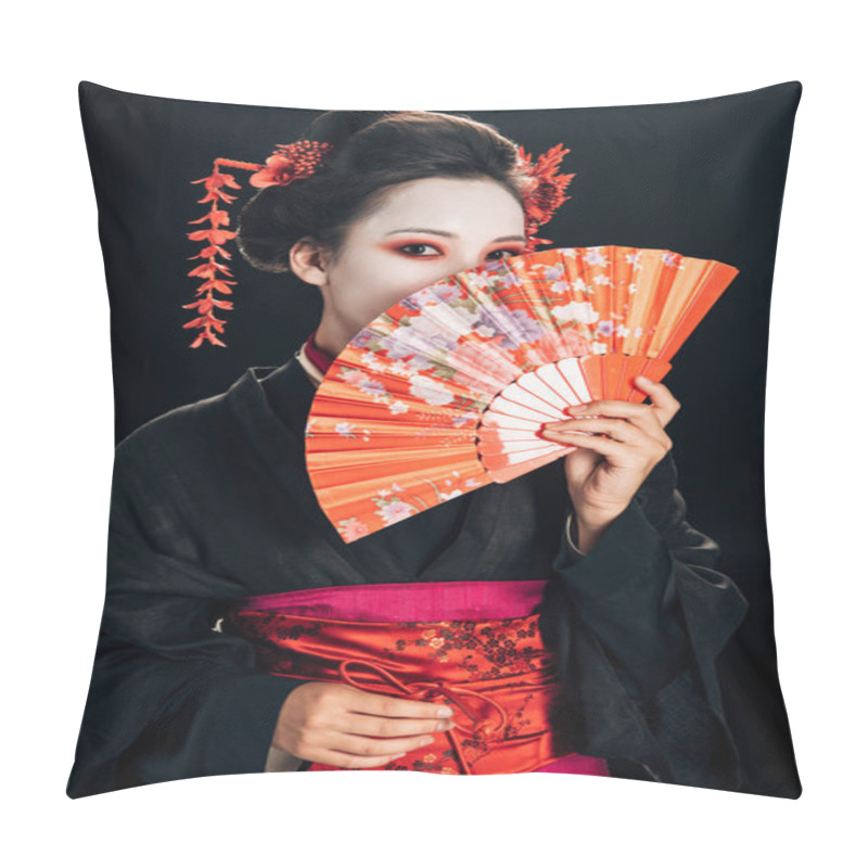 Personality  geisha in black kimono with red flowers in hair hiding face behind traditional hand fan isolated on black pillow covers