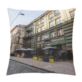 Personality  LVIV, UKRAINE - OCTOBER 23, 2019: Street Cafe With Plants In Flowerpots Near Old House With Latin Lettering  Pillow Covers