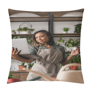 Personality  Smiling African American Woman Holding Laptop And Potted Plant During Video Call Near Blurred Rack With Flowerpots Pillow Covers