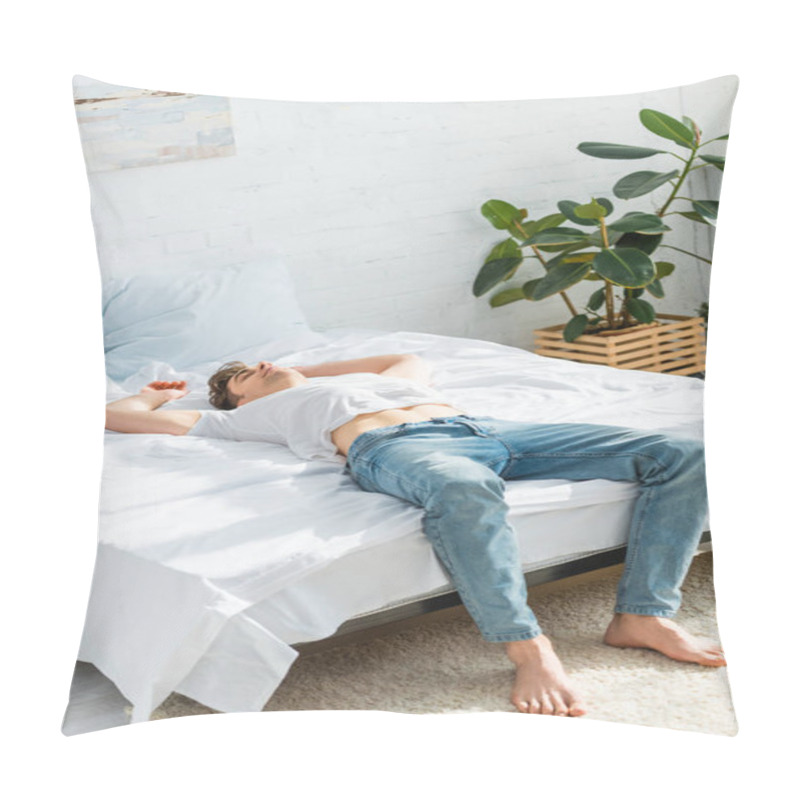 Personality  man in t-shirt and jeans lying on back on bed in bedroom  pillow covers