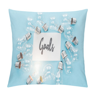 Personality  Top View Of 'goals' Word Written In Cursive On Card Surrounded By Circle Of Light Bulbs On Blue Background, Goal Setting Concept Pillow Covers