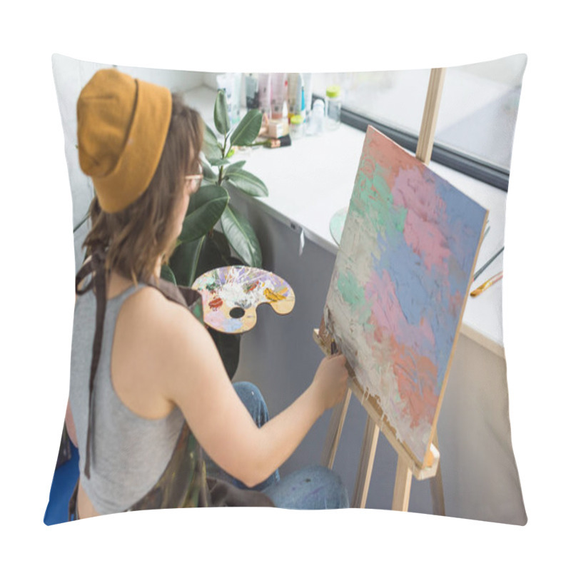 Personality  Young artistic girl working with painting knife and canvas in light studio pillow covers