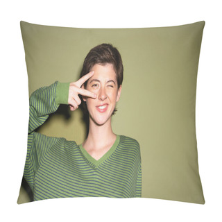 Personality  Cheerful Woman In Striped Jumper Showing Victory Sign Near Face And Winking At Camera On Green Background Pillow Covers