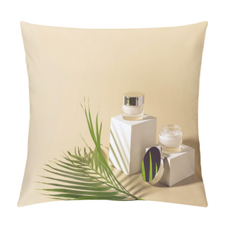 Personality  Close Up View Of Green Palm Leaf, Facial And Body Creams In Glass Jars On White Cubes On Beige Background Pillow Covers