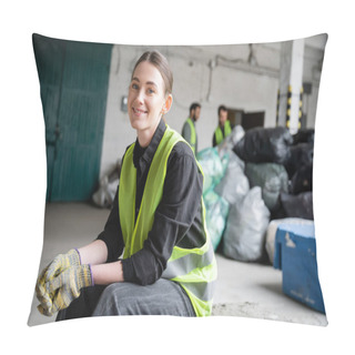 Personality  Cheerful Young Worker In Safety Vest And Gloves Looking At Camera While Resting And Sitting Near Blurred Plastic Bags In Garbage Sorting Center, Recycling Concept Pillow Covers