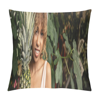 Personality  Positive Young African American Woman With Braces And Summer Outfit Looking At Camera Near Fresh Pineapple In Blurred Garden Center, Woman In Summer Outfit Posing Near Lush Tropical Plants, Banner Pillow Covers