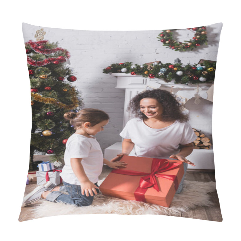 Personality  Mother with daughter touching big gift box near fireplace and pine at home pillow covers