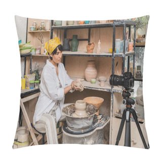 Personality  Young Asian Female Artisan In Workwear And Headscarf Holding Wet Clay Near Digital Camera On Tripod And Pottery Wheel In Ceramic Workshop, Clay Sculpting Process Concept Pillow Covers