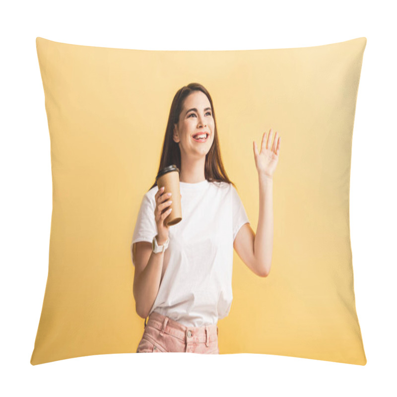 Personality  happy girl holding coffee to go and waving hand while looking away isolated on yellow pillow covers