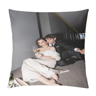 Personality  Happy Groom In Black Suit Holding Bottle And Sitting Near Charming Bride With Glass Of Champagne Next To Bridal Bouquet And High Heels On Floor In Corridor Of Modern Hotel  Pillow Covers
