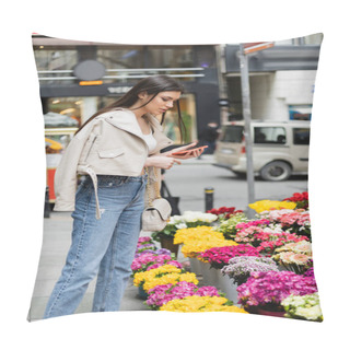 Personality  Brunette Woman With Long Hair Standing In Beige Leather Jacket, Denim Jeans And Handbag With Chain Strap Holding Smartphone While Looking At Flowers Near Blurred Cars On Street In Istanbul, Vendor Pillow Covers