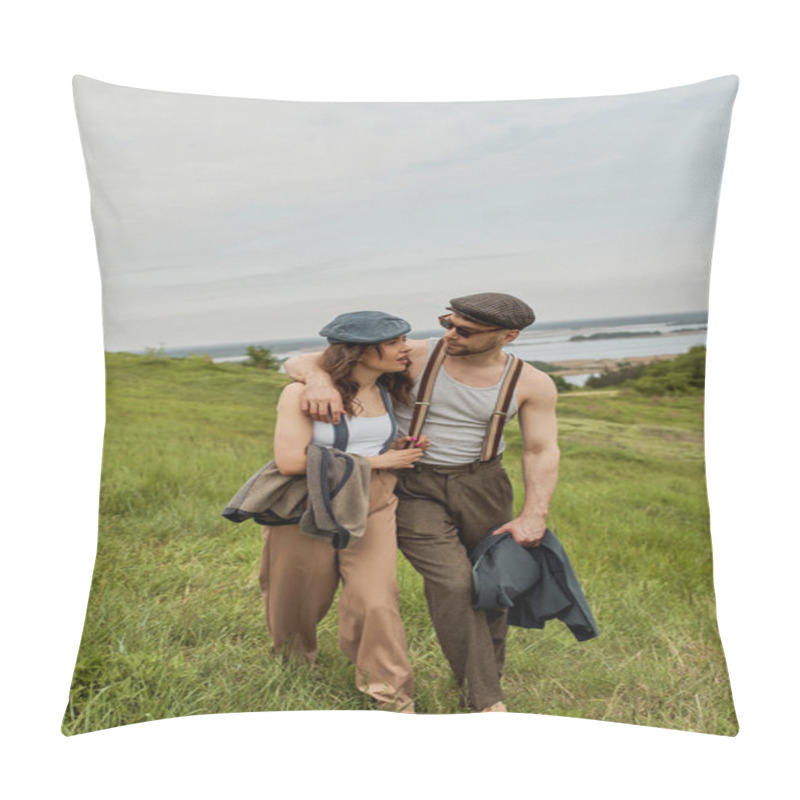 Personality  Fashionable man in vintage outfit and sunglasses hugging brunette girlfriend and talking while walking on blurred grassy hill with cloudy sky at background, stylish partners in rural escape pillow covers