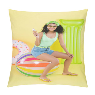 Personality  Full Length Of Positive African American Young Woman Sitting On Beach Ball And Holding Ice Cream Near Inflatable Mattress And Ring On Yellow  Pillow Covers