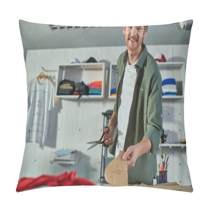 Personality  Smiling Redhead Craftsman Looking At Camera While Holding Scissors And Sewing Pattern Near Fabric On Table In Print Studio, Multitasking Business Owner Managing Multiple Project Pillow Covers