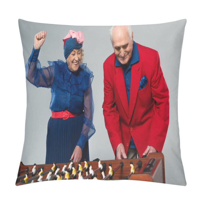 Personality  excited elderly couple in stylish clothes playing table football with win gesture on grey pillow covers