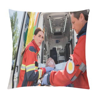 Personality  Selective Focus Of Paramedic Looking At Camera Near Patient On Stretcher And Colleague Outdoors  Pillow Covers