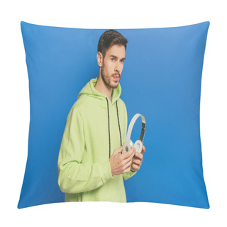 Personality  Thoughtful Young Man Holding Wireless Headphones While Looking Away On Blue Background Pillow Covers