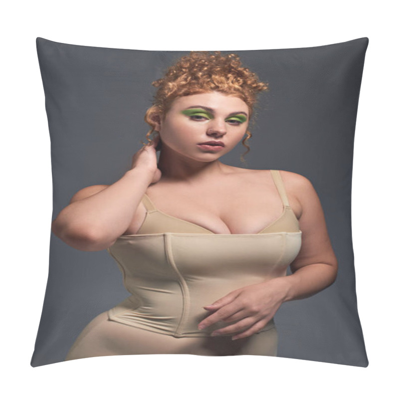 Personality  charming redhead and curvy woman in taupe underwear touching neck on and posing on dark grey pillow covers