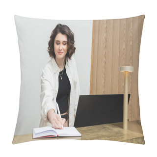 Personality  Friendly Concierge In Stylish Casual Clothes, With Wavy Brunette Hair Writing In Notebook Near Computer Monitor And Lamp While Working At Reception Desk In Lobby Of Contemporary Hotel Pillow Covers