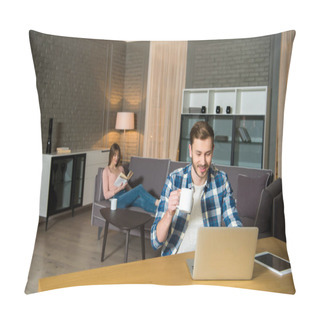 Personality  Man With Cup In Hand Using Laptop While Woman Reading Book On Couch In Living Room In Modern Design Pillow Covers