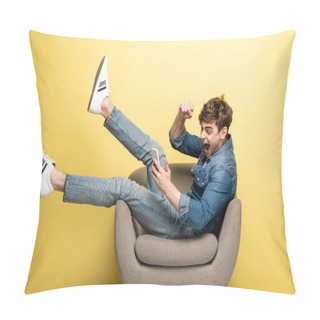 Personality  Excited Young Man Showing Yes Gesture While Sitting In Armchair And Using Smartphone On Yellow Background Pillow Covers