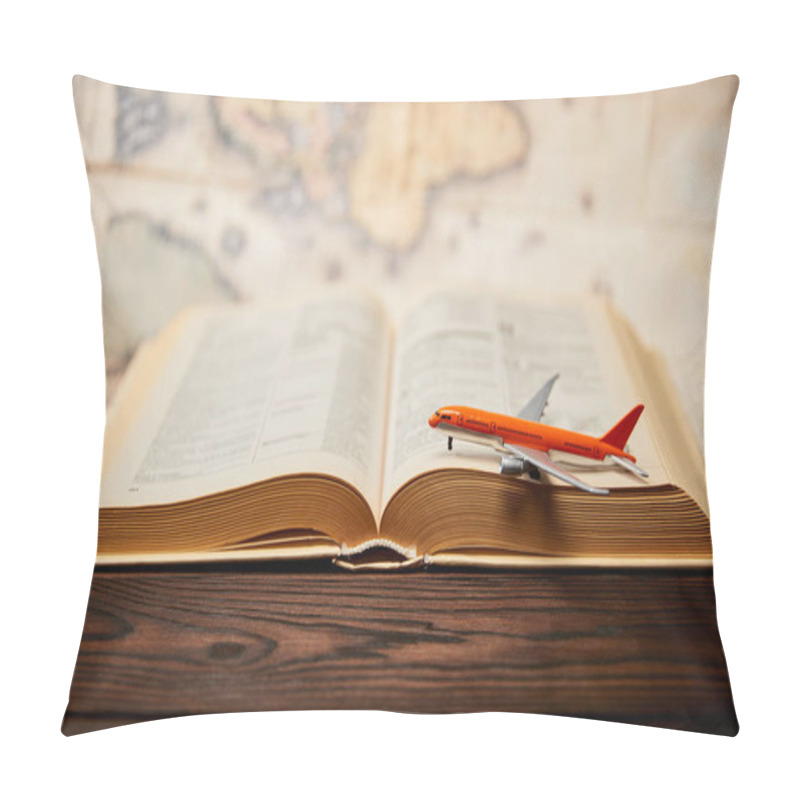 Personality  Selective focus of toy plane, book and map on wooden table pillow covers