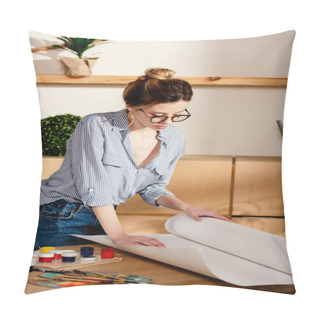 Personality  Stylish Female Artist In Eyeglasses Rolling Canvas On Table With Painting Supplies  Pillow Covers