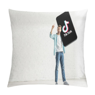 Personality  KYIV, UKRAINE - FEBRUARY 21, 2020: Surprised Man Showing Solution Gesture While Holding Model Of Smartphone With TikTok App At Home  Pillow Covers