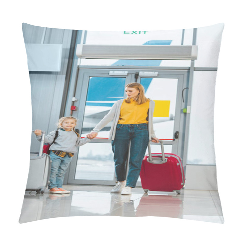 Personality  cheerful mother looking at daughter while holding hands in airport pillow covers