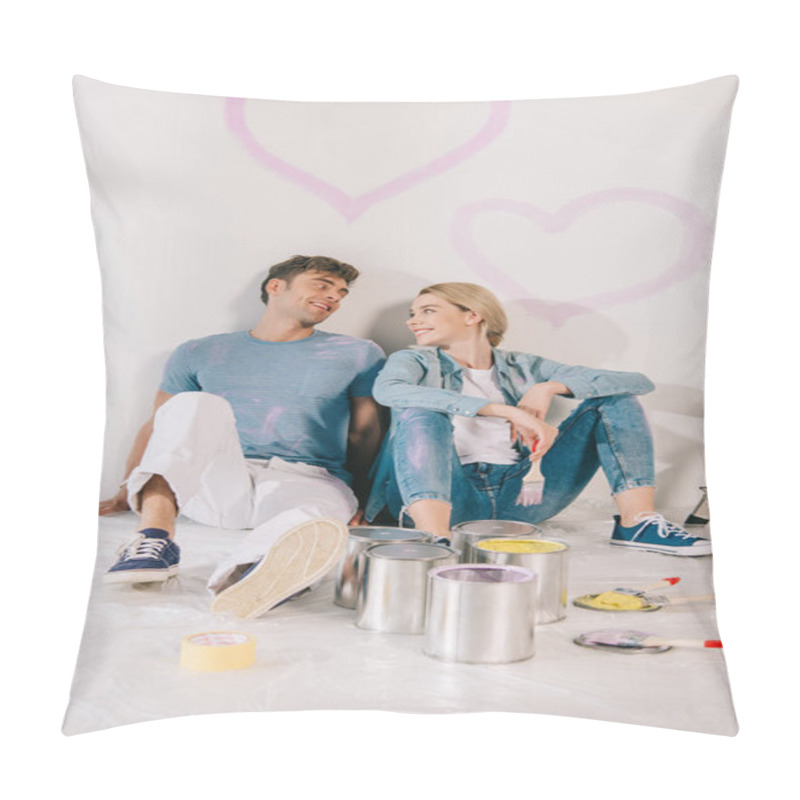 Personality  happy young couple sitting on floor by white wall under drawn pink hearts pillow covers