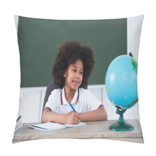 Personality  Smiling African American Pupil Writing On Notebook Near Blurred Globe On Desk  Pillow Covers