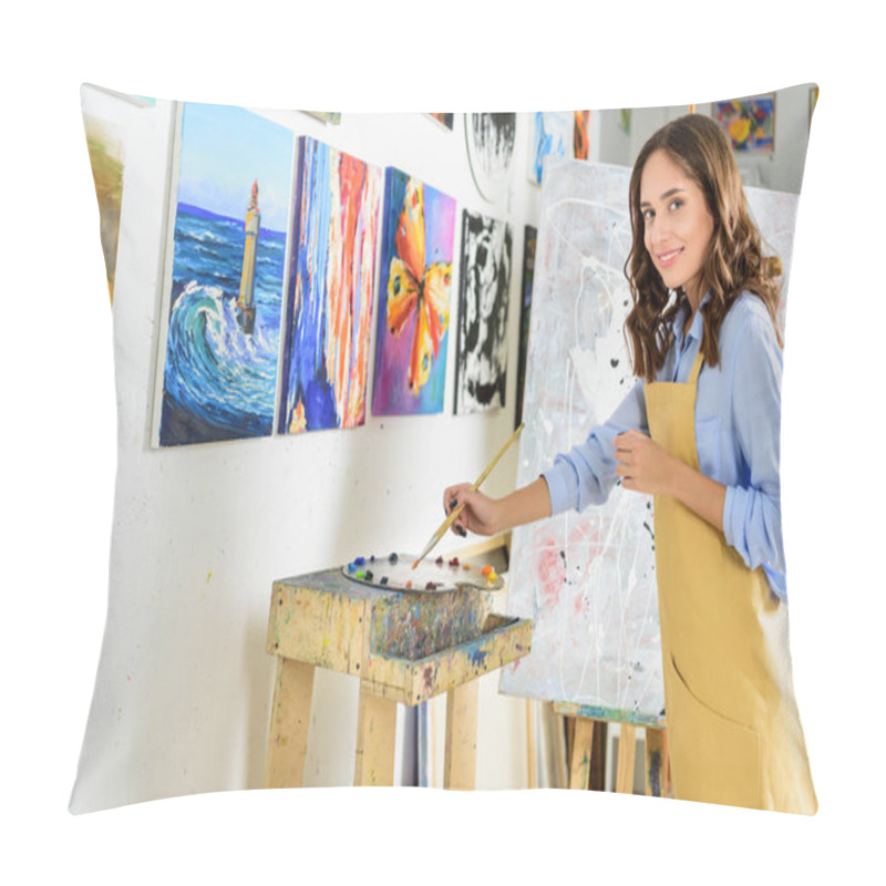 Personality  side view of beautiful female artist taking paint from palette in workshop pillow covers