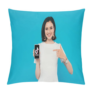 Personality  KYIV, UKRAINE - JULY 3, 2019: Smiling Elegant Woman In Dress Pointing With Finger At Smartphone With Tiktok Logo Isolated On Blue Pillow Covers