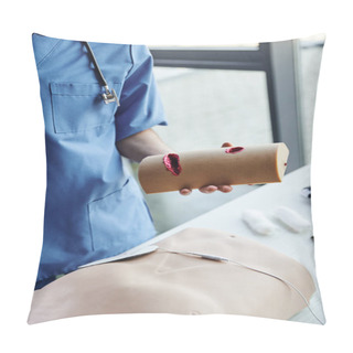 Personality  Cropped View Of Professional Paramedic In Blue Uniform Holding Wound Care Simulator Near CPR Manikin And Bandages On Blurred Background In Training Room, Critical Skills Development Concept Pillow Covers