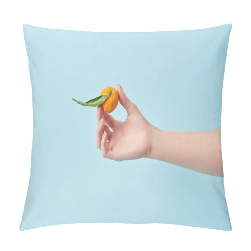 Personality  cropped view of woman holding tangerine with green leaf in hand isolated on blue  pillow covers