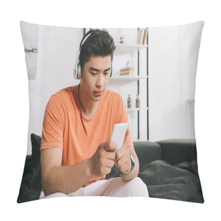 Personality  Thoughtful Asian Man Listening Music In Headphones And Using Smartphone While Sitting On Sofa At Home Pillow Covers