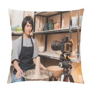 Personality  Young Asian Brunette Craftswoman In Apron Looking At Blurred Digital Camera On Tripod Near Wet Clay On Pottery Wheel And Rack In Ceramic Workshop, Pottery Tools And Equipment Pillow Covers