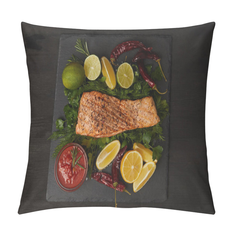 Personality  top view of grilled salmon steak, pieces of lime and lemon, chili peppers and sauce on black surface pillow covers
