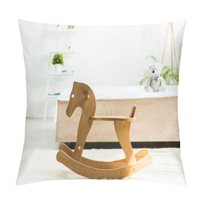 Personality  selective focus of wooden rocking horse near bed with white bedding and teddy bear pillow covers