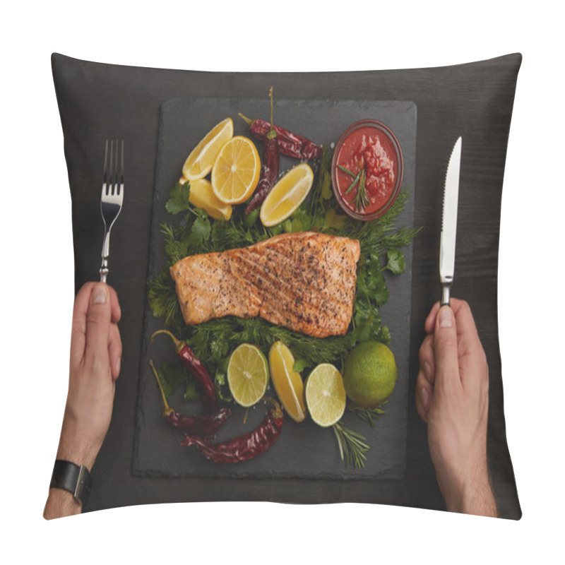 Personality  partial view of male hands with cutlery, grilled salmon steak, sauce and arranged citrus fruits on black surface pillow covers