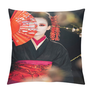 Personality  Selective Focus Of Beautiful Geisha In Black Kimono With Red Flowers In Hair Holding Hand Fan In Front Of Face And Sakura Branches Isolated On Black Pillow Covers