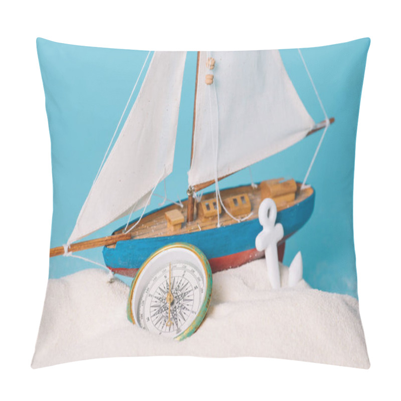 Personality  close up view of decorative ship near anchor and compass in white sand isolated on blue pillow covers