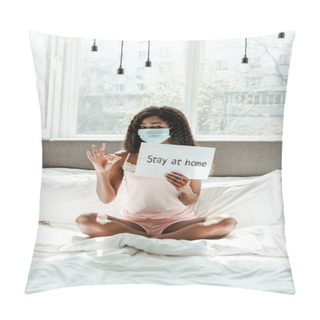 Personality  African American Woman In Medical Mask With Crossed Legs Showing Okay Sign And Placard With Stay At Home Inscription On Bed In Bedroom Pillow Covers